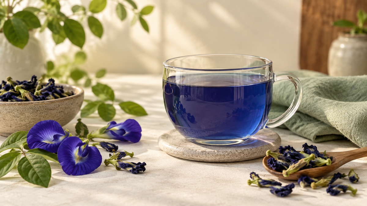 Blue butterfly pea flower tea with dried Aparajita flowers on a warm cream table